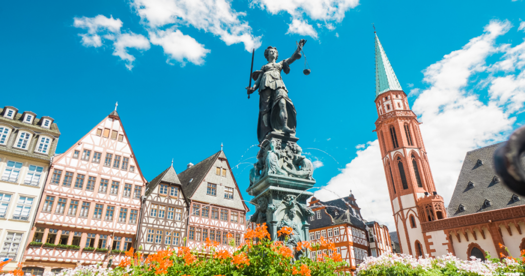 The historic Römerberg square in Frankfurt, Germany, with traditional half-timbered buildings, Lady Justice statue, and the Old Nikolai Church tower. A perfect starting point for your perfect backpacking Europe itinerary, showcasing the blend of medieval and modern architecture in this German city.